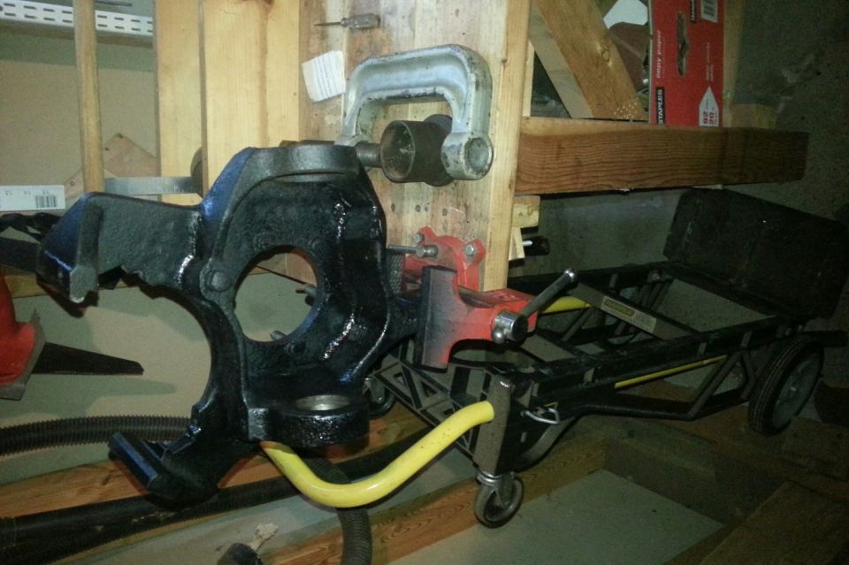 Black painted steering knuckle on a workbench next to a cart and tools
