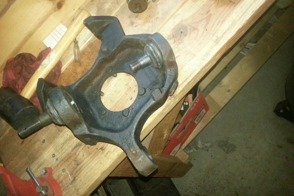 Blue painted steering knuckle resting on a wood workbench