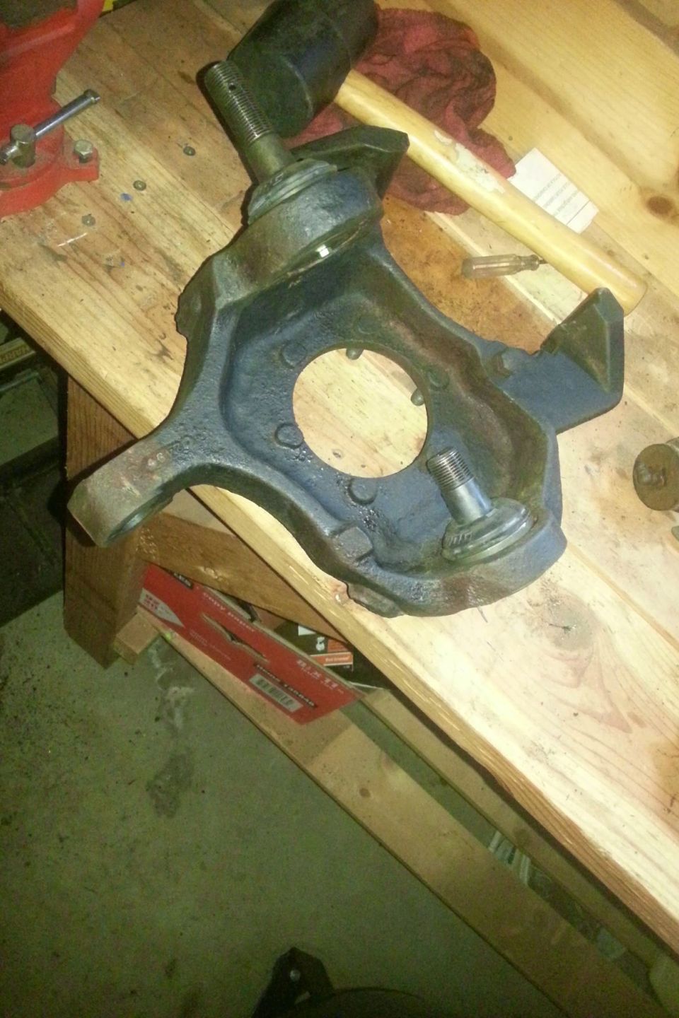 Blue painted steering knuckle resting on a wood workbench
