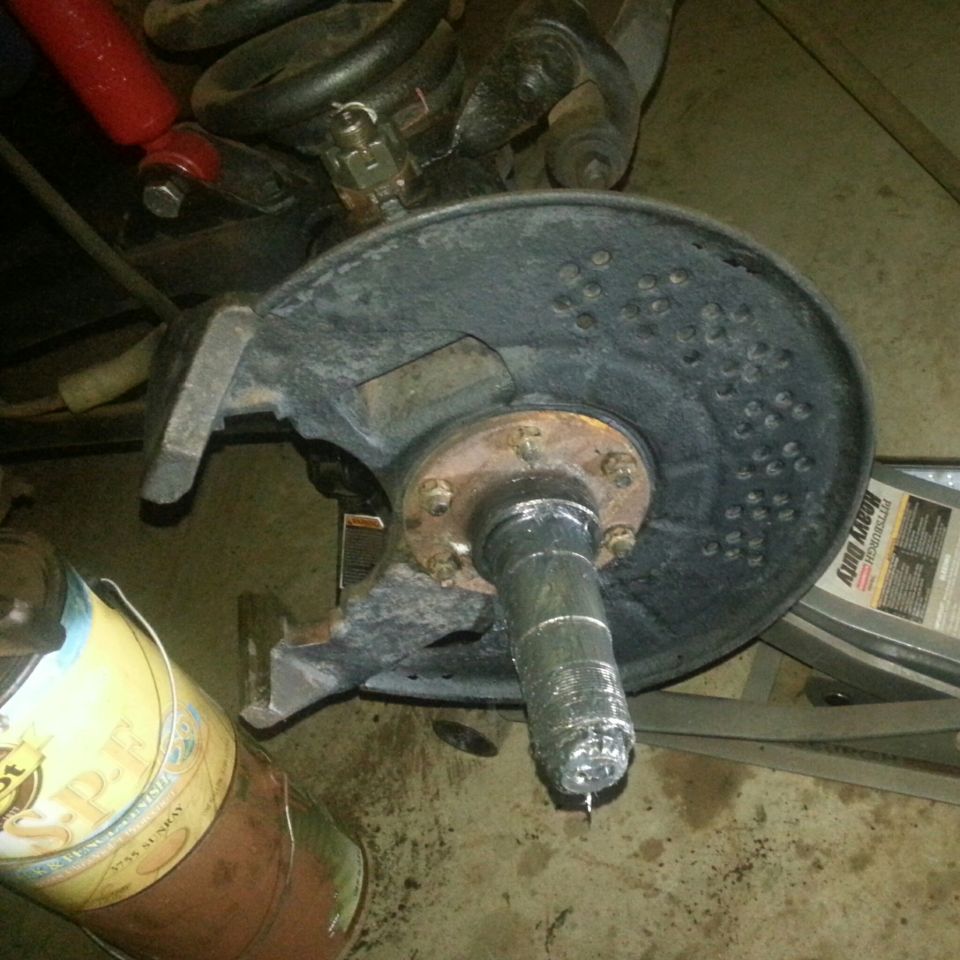 Vehicle wheel hub assembly with brake rotor and spindle, on garage floor.