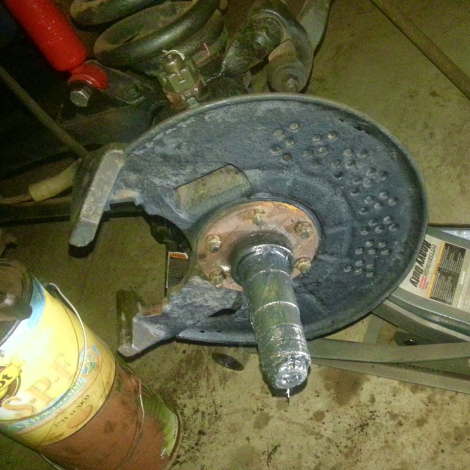 Vehicle front suspension and brake assembly with rotor, spindle, and caliper bracket.