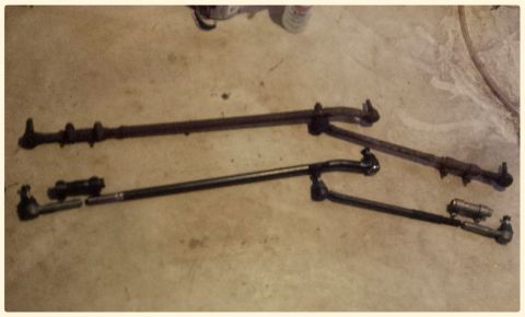 Two steering linkage assemblies on a concrete floor.