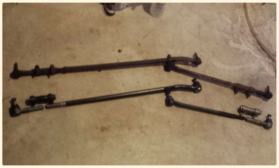 Two steering linkage assemblies on a concrete floor.