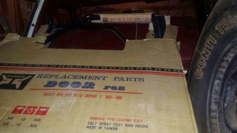 Cardboard box for a 1980-1986 Ford Bronco door, with a tire to the right.