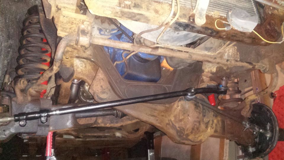 Underside of a vintage Ford Bronco showing suspension, steering, and engine.