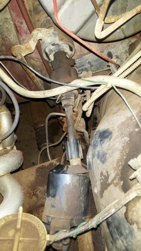 1984 Ford Bronco steering column with universal joints and rubber boot, covered in dirt.