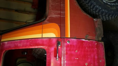 Red vehicle with retro stripe graphic, showing rust on the rear quarter panel.