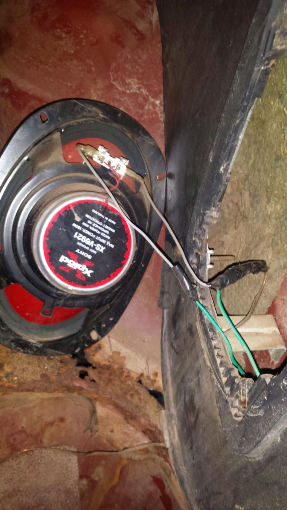 Sony Xplod speaker with visible wiring and rust in a vehicle.