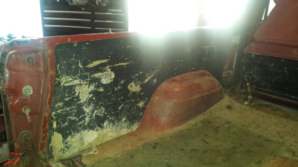 Interior of a red Ford Bronco, rear passenger side panel and wheel well.