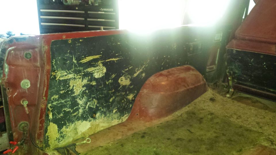 Interior rear passenger side of a red vehicle, showing wheel well, door panel, and carpet.