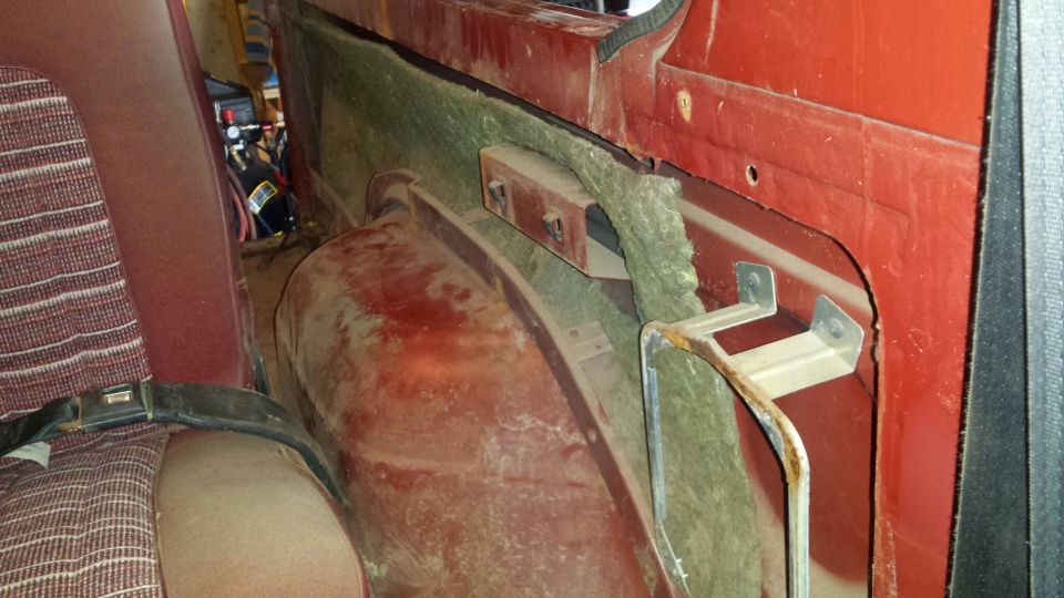 Interior of a red vehicle showing rear seat, insulation, and a metal bracket.
