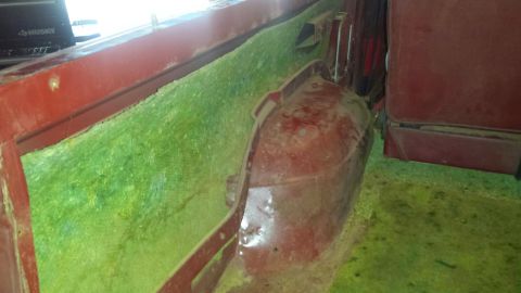 Interior of a vehicle showing red seats, green insulation, and a red wheel well.