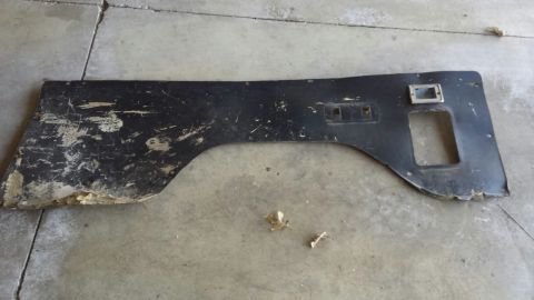 Black, damaged interior trim piece with cutouts on a concrete floor