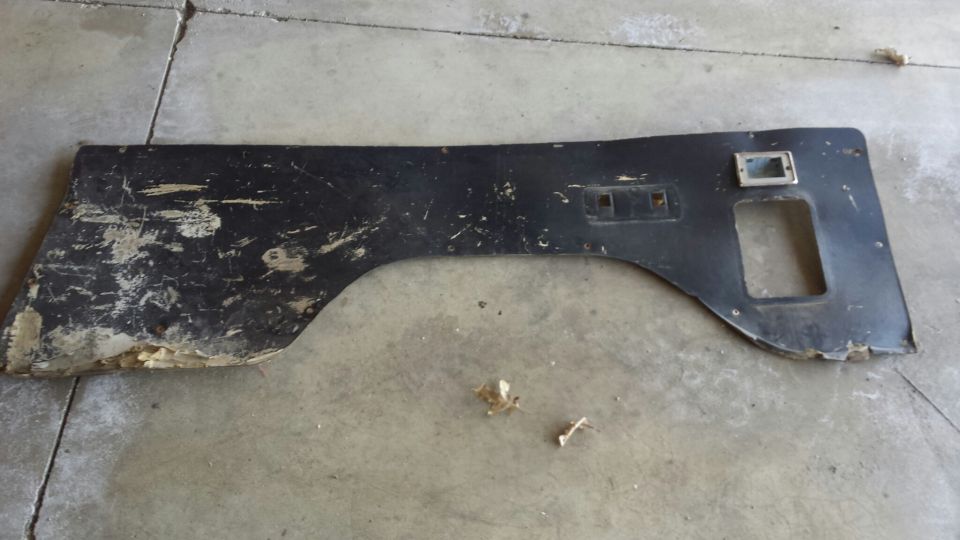 Black, damaged interior trim piece with cutouts on a concrete floor