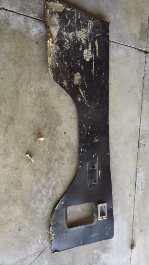 Damaged black interior trim piece with cutouts on a concrete floor.
