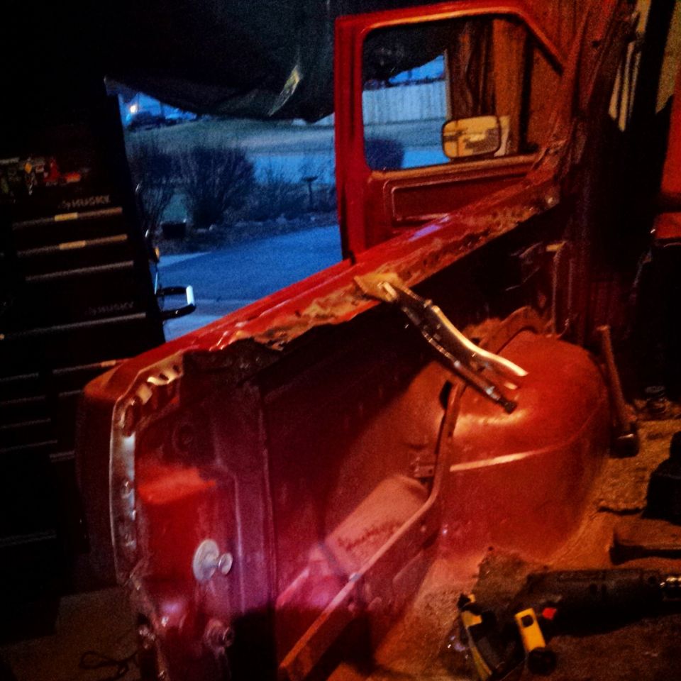 Red Ford Bronco interior with door open, showing removed body panels and tools.