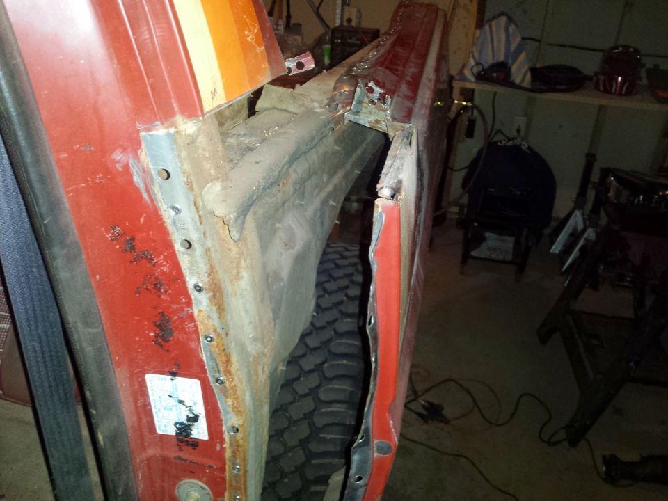 Close-up of rusted and repaired rocker panel on a red vehicle.