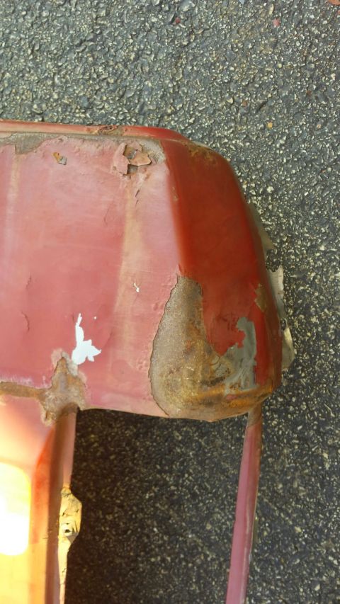 Red vehicle body panel with rust and peeling paint.
