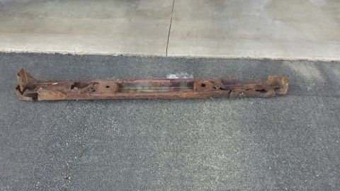 Heavily rusted metal frame part on asphalt