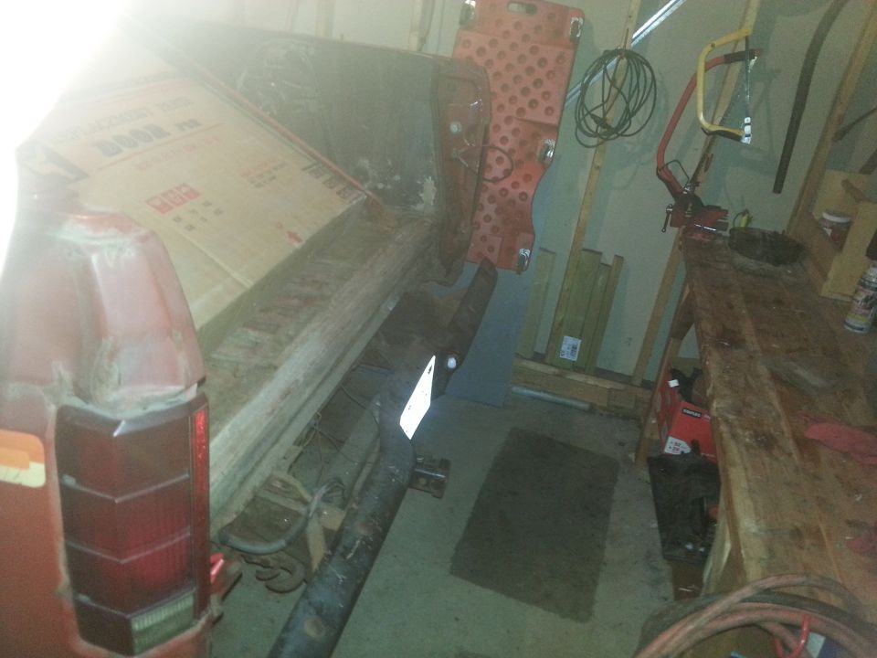 Rear of red vehicle with cardboard box in bed, workshop background