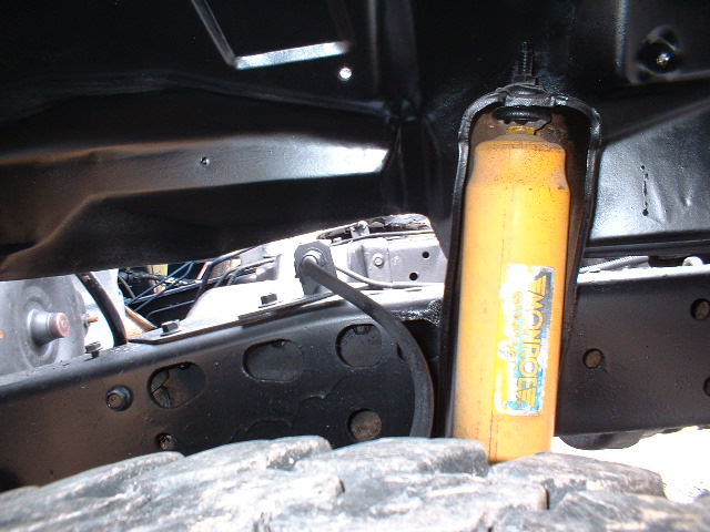Truck chassis with yellow Monroe shock absorber and large tire tread visible