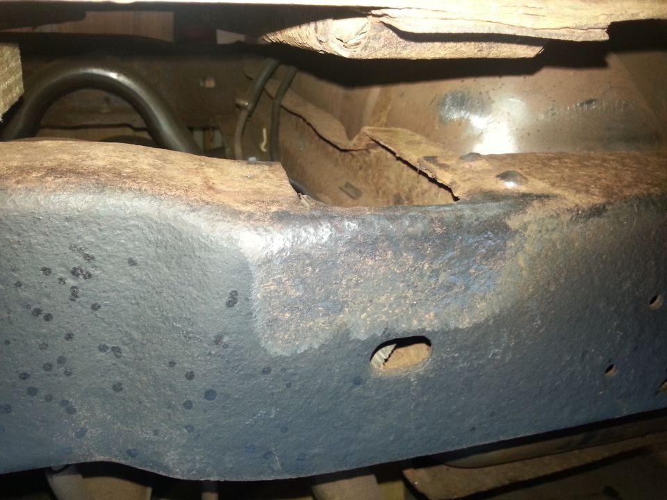 Heavily rusted and damaged vehicle frame with a crack and holes.
