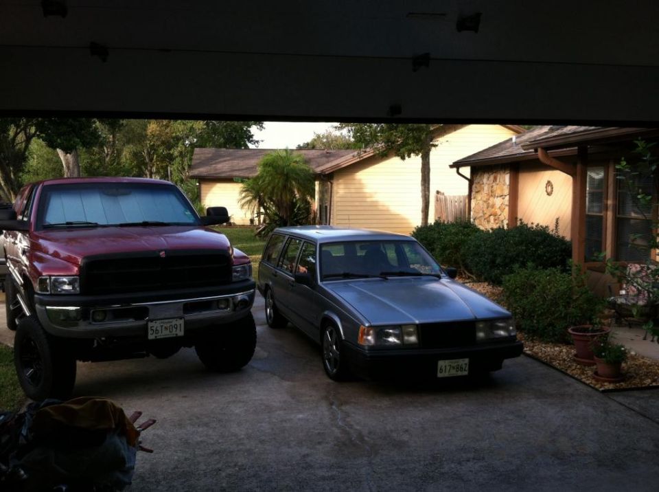 Red Dodge Ram pickup and silver Volvo 940 station wagon parked in a driveway.