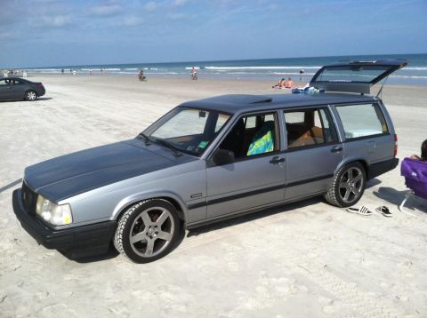 1991 Volvo 940 - Silver 1991 Volvo 940 station wagon with its trunk open, parked on a beach.