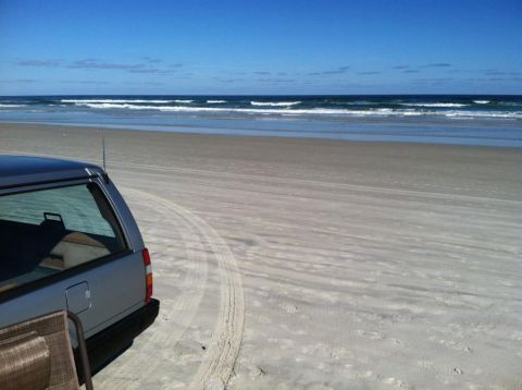 1991 Volvo 940 - A silver station wagon sits on a sandy beach, with the ocean and waves in the background.