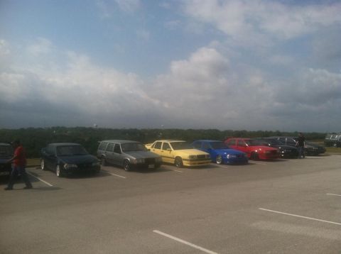 1991 Volvo 940 - A line of Volvos, including a wagon and several sedans, are parked under a cloudy sky.