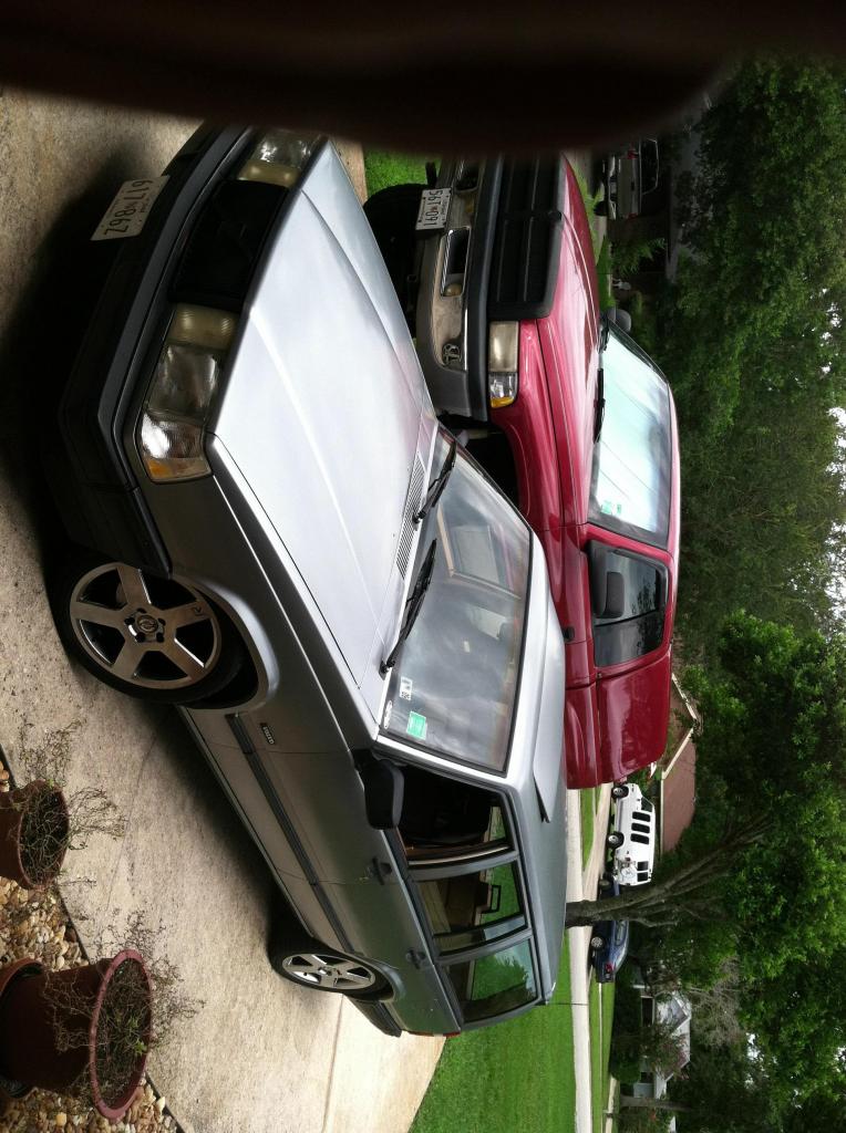 1991 Volvo 940 station wagon parked next to a red pickup truck