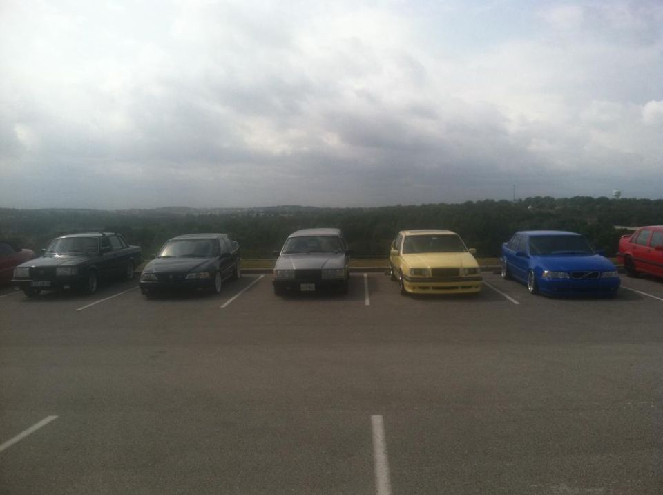 Several cars parked in a lot under a cloudy sky