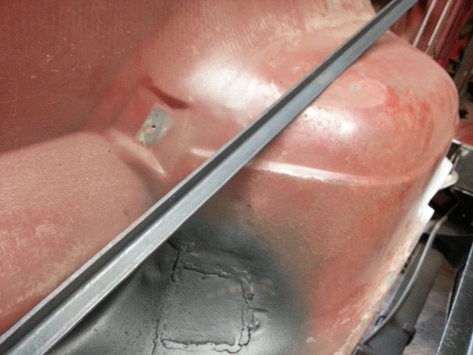Close-up of red metal panel with gray trim, possibly from a vehicle's undercarriage