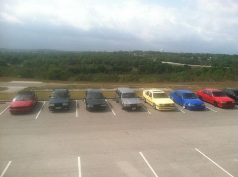 1991 Volvo 940 - Multiple cars are parked in a lot, with a wooded landscape and overcast sky visible.