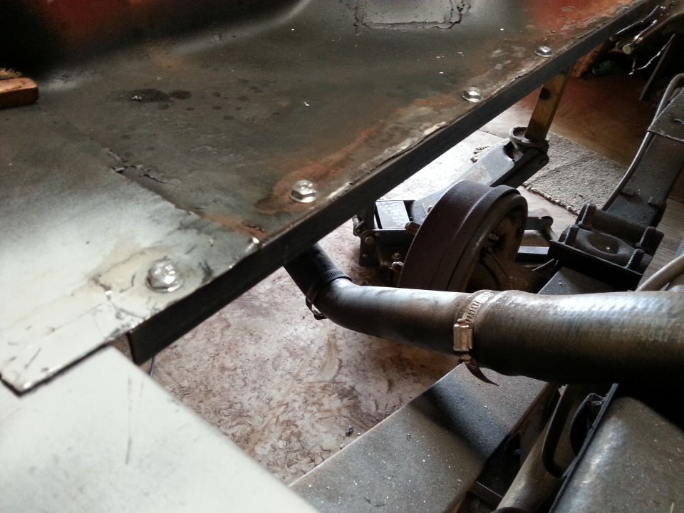 Undercarriage of a vehicle with a jack, brake drum, and hose