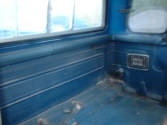 Interior of blue pickup truck bed with ribbed paneling and a speaker grille