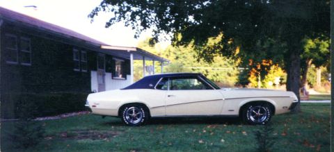 1969 Mercury Cougar - A 1970 Mercury Cougar with a blue vinyl top sits parked in front of a house on a sunny day.