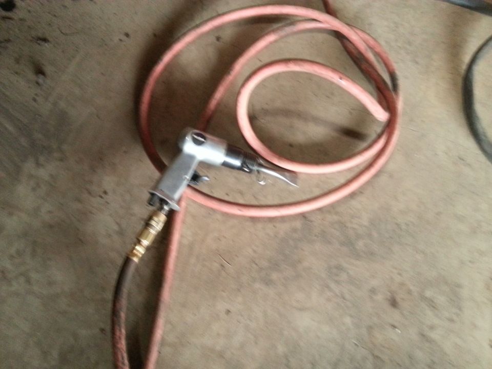 air hammer with orange hose coiled up on concrete floor
