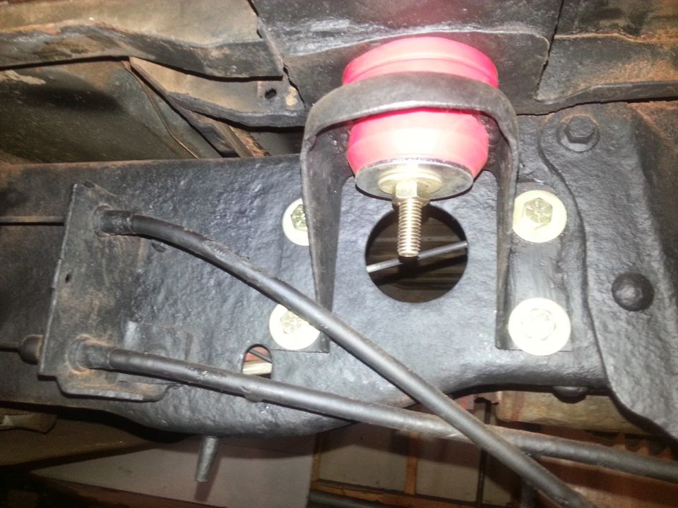 Underside of vehicle frame with red body mount bushing and black cables.