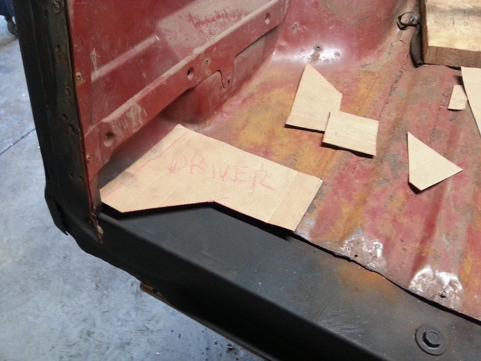 Cardboard templates on a rusty vehicle floor, one labeled "DRIVER".