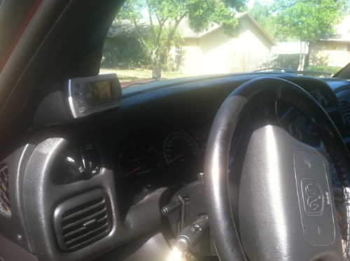 Interior view of a vehicle dashboard with a digital display unit and steering wheel.