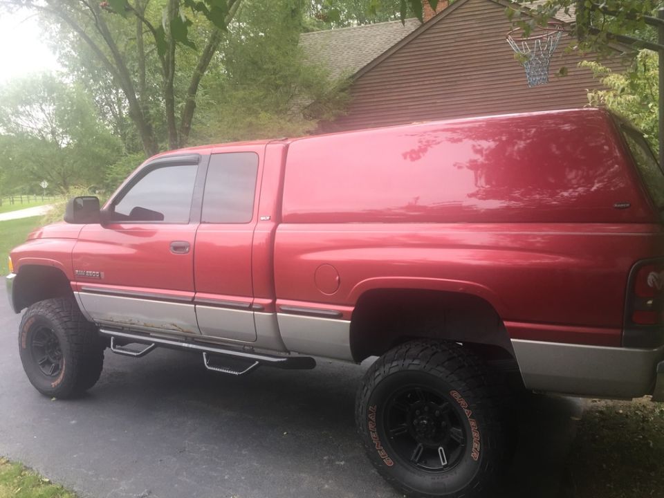 Red 1999 Dodge 2500 pickup truck with camper shell parked on driveway.