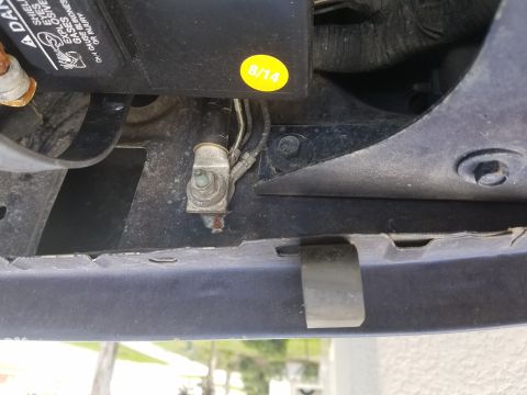 1994 Ford Bronco - Photograph of a ground cable terminal in the engine bay beside a yellow dated sticker.