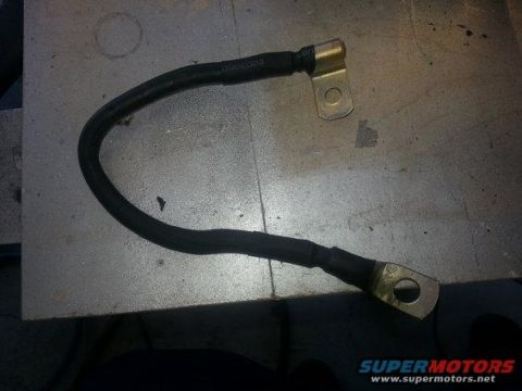 1994 Ford Bronco - Photograph of a battery ground cable with two ring terminals laid on a workbench.