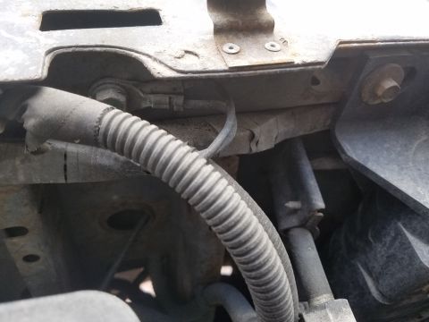 1994 Ford Bronco - Photograph of a corrugated wire loom routed across the frame and inner fender.