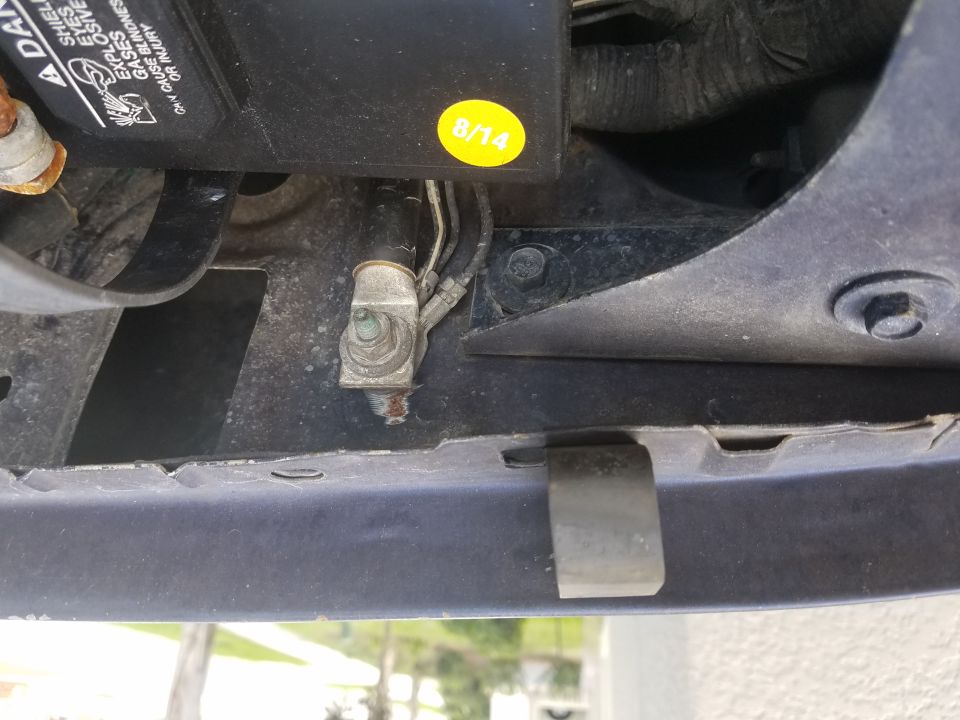 Photo of a ground terminal and cable near a yellow 8/14 sticker on a vehicle