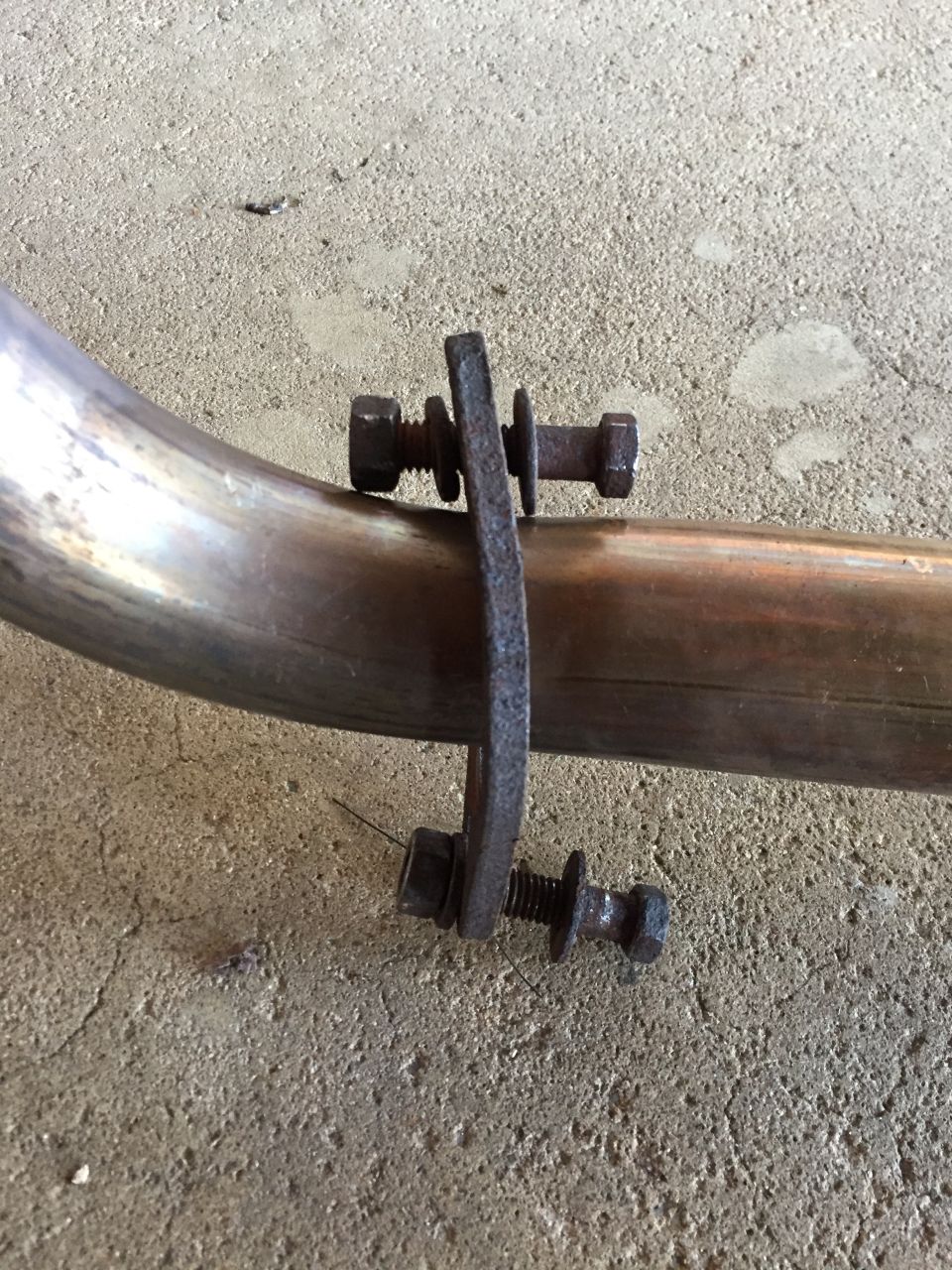 Rusty exhaust pipe clamp with bolts and washers on a metal pipe