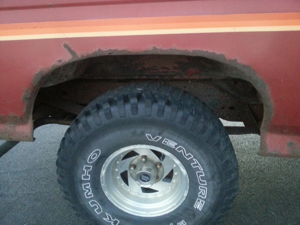 Red Ford Bronco rear wheel well with rusted fender and Kumho Venture tire.