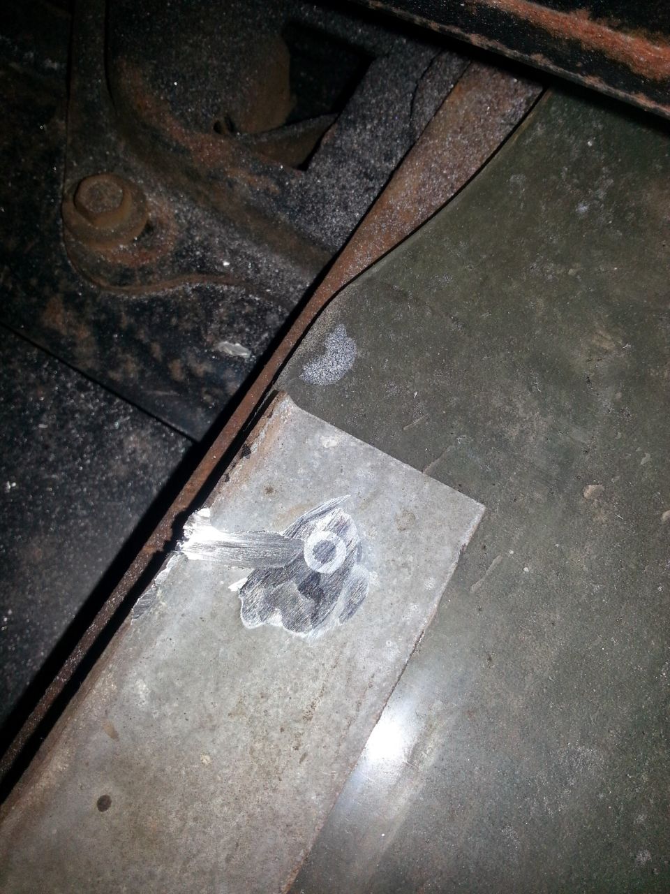 Close-up of a metal plate with a hole, showing dust and rust on surrounding metal.