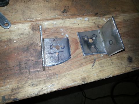 Two metal brackets on a wooden workbench.